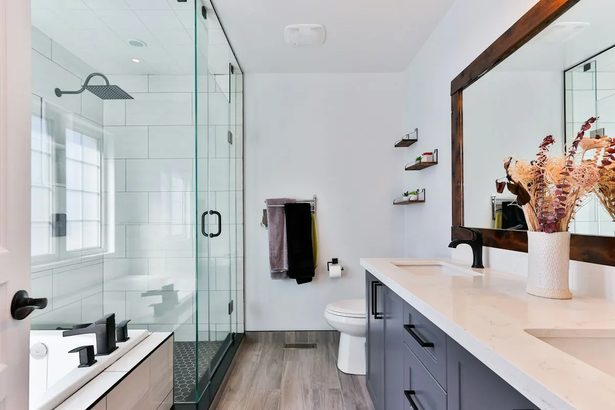 Bathroom with a glass shower enclosure, a dark vanity and a wood-look floor