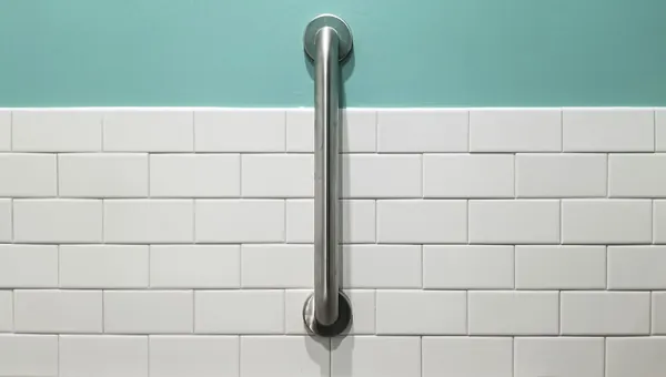 Stainless steel grab bar mounted vertically on white subway tile