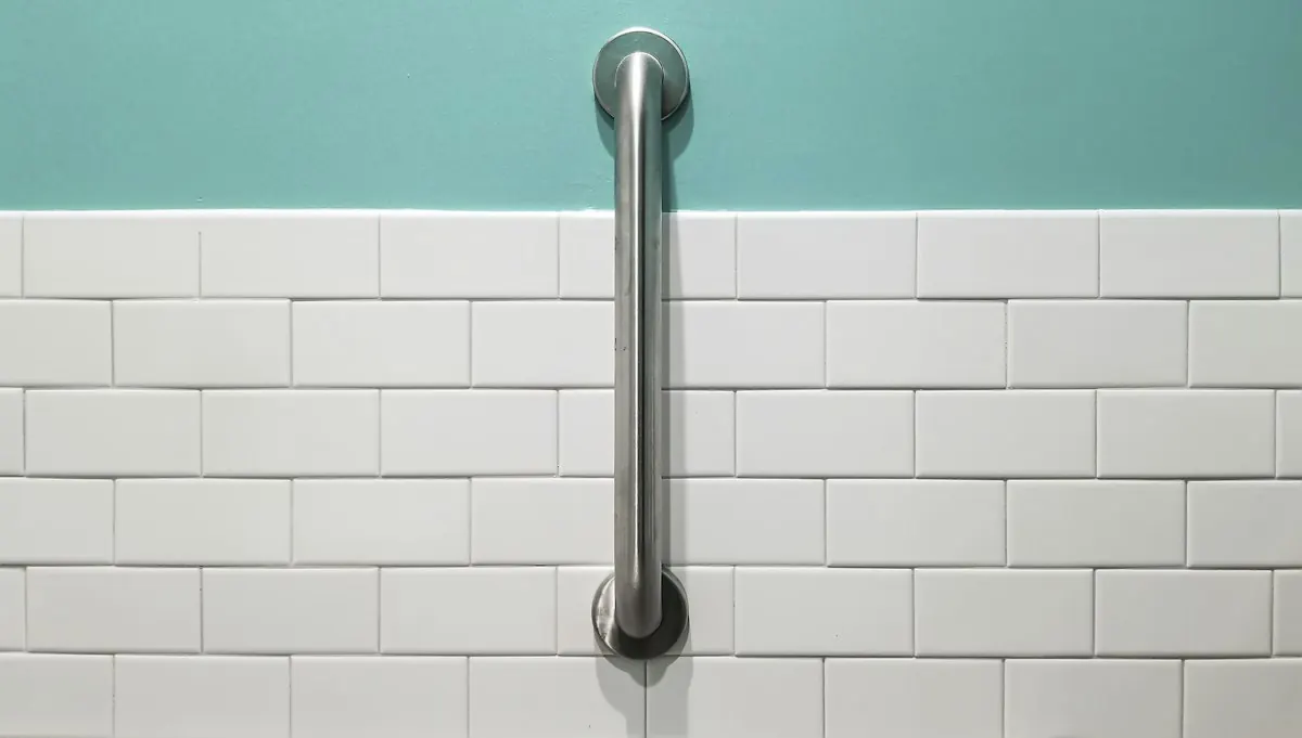 Stainless steel grab bar mounted vertically on white subway tile