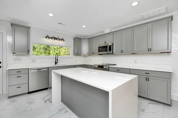 Gray shaker cabinets with a white waterfall quartz island and marble-look floor tile