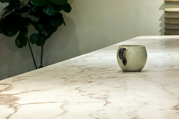 Close view of a veined white marble countertop with a single mug on it