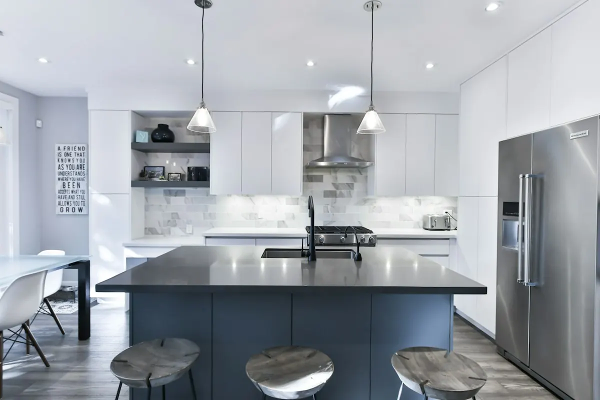 Open-plan kitchen with a dark island, pendant lights and a dining area beyond