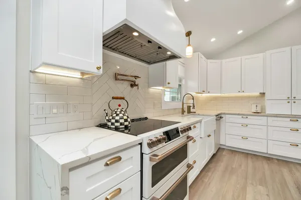 White shaker cabinets with under-cabinet lights and a range under a hood