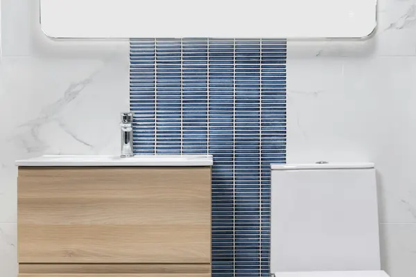 Small bathroom with a wall-hung wood vanity, a toilet and a vertical strip of blue tile