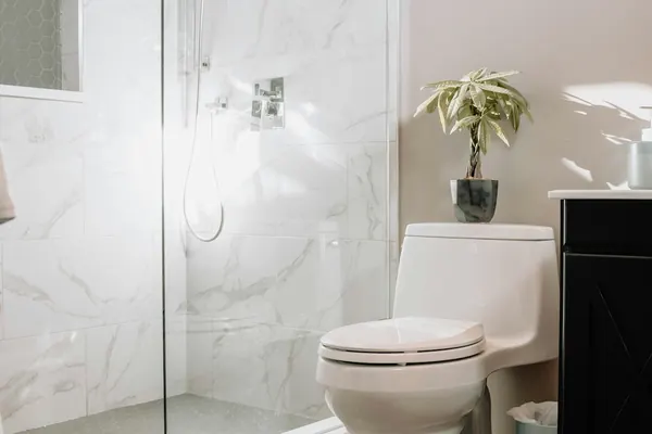 Walk-in shower with marble-look tile, a recessed niche and a glass panel